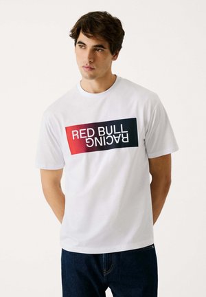 Baltas medvilninis marškinėlis su spalvingu "RED BULL RACING" grafiku raudonai ir mėlynai. Trumpomis rankovėmis ir apvalia iškirpte.