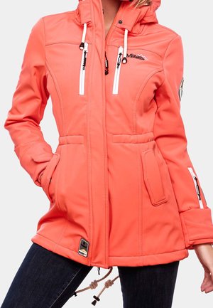 Mujer con chaqueta softshell coral con capucha, bolsillos con cremallera blancos y pantalones negros sobre un fondo liso.