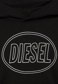 Μαύρο φούτερ με κουκούλα που διαθέτει μεγάλο λευκό οβάλ λογότυπο με τη λέξη "DIESEL" σε έντονα γράμματα, κατασκευασμένο από απαλό ύφασμα με λεία υφή.