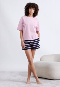 Hellrosa Baumwoll-T-Shirt und marineblaue gestreifte Shorts, mit entspanntem Schnitt und kurzen Ärmeln. Glatte Textur, lässiges Design.