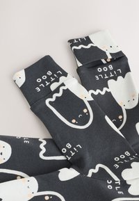 Čierne ponožky s hravými vzormi duchov v bielej a svetlo šedej farbe, s nápisom "little boo" v bielej. Mäkká látka a dizajn po stred lýtka.