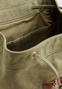 Πράσινη υφασμάτινη τσάντα με κορδόνι κλεισίματος, με καφέ δερμάτινες λεπτομέρειες και εσωτερική τσέπη. Υφή υφάσματος, εσωτερικό χωρίς φόδρα.