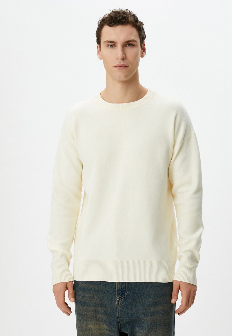 Helle Cremepullover mit Rundhalsausschnitt, gerippten Bündchen und Saum. Aus weichem Material gefertigt, mit lockerer Passform und langen Ärmeln.