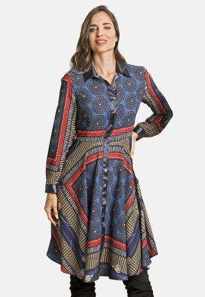 Vestido de camisa multicolorido con patrones circulares y geométricos en azul, rojo y verde. Mangas largas y botones frontales, ajustado en la cintura.