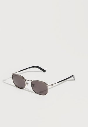 Silver metal-framed sunglasses with dark tinted octagonal lenses and black curved temple tips laid on a light surface.