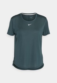 Camiseta de manga corta Nike dry-fit en un color verde azulado oscuro. Presenta un cuello redondo y un pequeño logo blanco en el pecho. Tela suave y ligera.