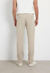 Pantaloni beige realizzati in tessuto leggero, con design a gamba dritta, due tasche posteriori con bottoni e dettagli di cucitura minimi.