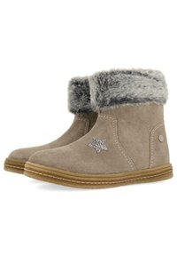 Botas de tobillo de ante beige con trim de piel de pelo gris, que presentan un acento de estrella brillante y una suela de goma con detalles de costura.