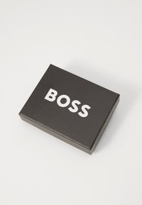 Scatola rettangolare nera con finitura opaca, caratterizzata dal testo bianco "BOSS" ben in evidenza sulla parte superiore.