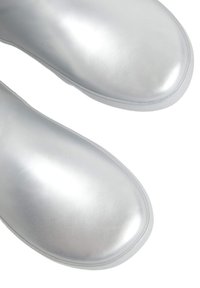 Botas de tobillo plateadas con un acabado metálico suave y brillante; punta redondeada y diseño minimalista; material ligero y sin herrajes visibles.