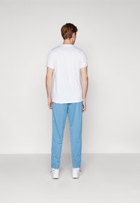 Camiseta blanca de manga corta combinada con pantalones azul claro. El conjunto presenta un corte relajado, una textura suave y un diseño sencillo. Zapatillas blancas completan el look.