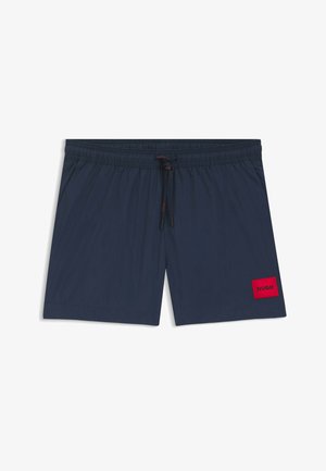 Costume da bagno blu navy con vita elasticizzata e coulisse, caratterizzato da una toppa rettangolare rossa con la scritta "HUGO" sulla gamba sinistra.