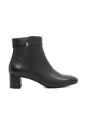 Bottine en cuir noir avec un petit talon bloc et une fine lanière autour du bord supérieur avec une petite boucle en métal.