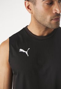 Zwart mouwloos sportshirt met een ronde, gestructureerde halslijn en een wit Puma-logo aan de linkerkant van de borst.