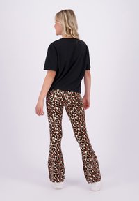 Svart t-skjorte med korte ermer, kombinert med utsvingte leggins med brunt og svart leopardmønster. Hvite sneakers fullfører antrekket.