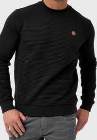 Zwarte sweatshirts met textuur, voorzien van een ronde halslijn, ribgebreide manchetten en zoom, en een klein rond logo op de borst.