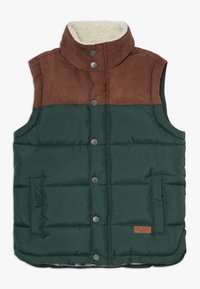 Chaleco acolchado en verde oscuro con parte superior de piel sintética marrón. Presenta un cuello alto, botones a presión y dos bolsillos frontales. El forro es de un patrón decorativo.