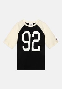 Schwarzes T-Shirt mit kurzen cremefarbenen Raglanärmeln, das auf der Vorderseite eine große weiße Zahl "92" zeigt. Aus Baumwollmaterial mit einem Rundhalsausschnitt.