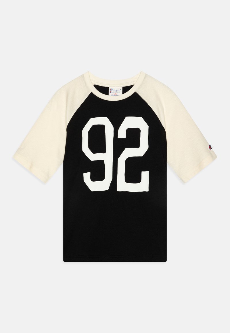 Schwarzes T-Shirt mit kurzen cremefarbenen Raglanärmeln, das auf der Vorderseite eine große weiße Zahl "92" zeigt. Aus Baumwollmaterial mit einem Rundhalsausschnitt.