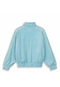 Felpa in velour azzurro chiaro, morbida, con colletto alto, vita ed elastici ai polsini, caratterizzata da piping giallo lungo le cuciture.