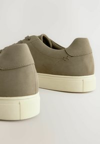 Baskets en daim vert olive avec une semelle en caoutchouc, présentant un bout rond, un design à lacets, et un minimum de détails de couture au talon.
