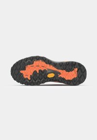 Black rubber outsole with an orange patterned section, featuring multidirectional lugs for traction and a yellow logo detail.