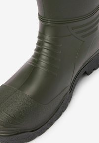Bota de goma en verde oscuro con un acabado texturizado. Presenta acentos de goma estriados y una suela gruesa y estampada para mayor tracción.