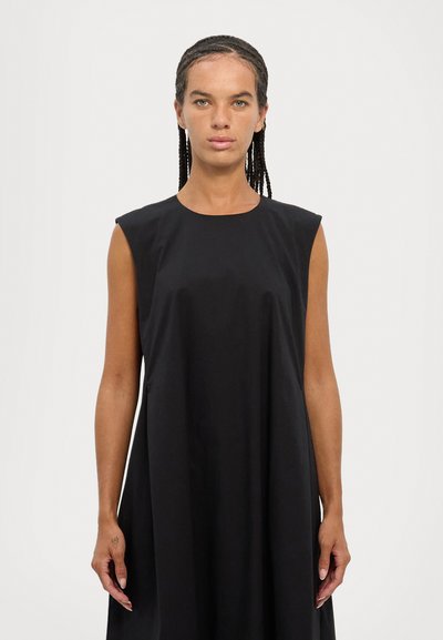 Black sleeveless dress made of smooth fabric, featuring a round neck and relaxed fit, falling to mid-calf with minimalistic design.