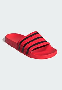 Rød slidesandal med tekstureret syntetisk overdel, der har tre sorte vandrette striber. Glat sål og åben tådesign.