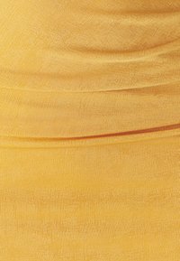 Tissu jaune côtelé avec une texture lisse, présentant de légers fronces et une ligne orange horizontale en bas.