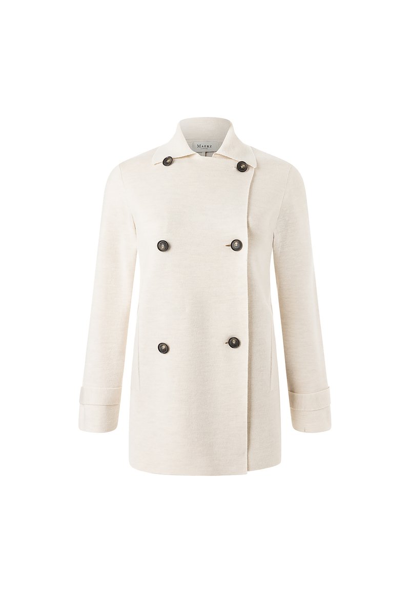 Kermanvärinen kaksinkertainen takki, joka on valmistettu tekstuurista kankaasta. Se on varustettu mustilla napilla ja käännettävällä kauluksella, jossa on taitetut hihansuut.