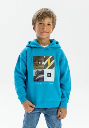 Un hoodie turquoise avec un graphisme carré comportant des images urbaines et du texte. Fabriqué en tissu doux avec une poche kangourou et des bords côtelés.