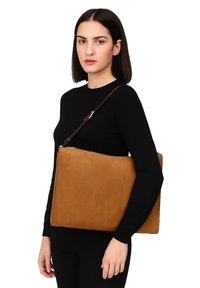 Borsa a tracolla in pelle tan con una texture liscia, forma rettangolare e spallaccio marrone. Presenta una chiusura con zip e un design minimalista.
