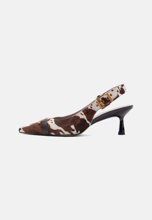 Slingback kitten heel shoe with brown and white cow print, pointed toe, black strap across front, and gold buckle detail on ankle strap.
