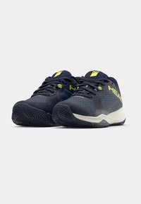 Kleitas zilas sporta apavi, izgatavoti no sintētiskiem materiāliem ar strukturētu sietu, ar baltu zoli un neona zaļām akcentiem.