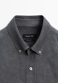 Donkergrijs overhemd met knoopsluiting en een knoopdown kraag, met drie zichtbare witte knopen, gelabeld Massimo Dutti.