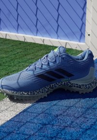 Blue athletic shoe with textured fabric, three black stripes, neon green accents, and a leopard print outsole, designed for traction.