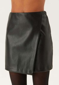 Zwarte leren mini-jurk met een wikkelontwerp, een gladde textuur en een hoge taille. Voorzien van een onzichtbare zijrits voor sluiting.