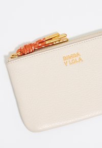 Light beige leather pouch with a textured finish, gold hardware, and an orange braided zipper pull. "BIMBA Y LOLA" embossed in gold.