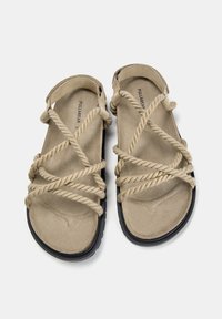 Sandale din suede bej, cu detalii complicate din sfoară pe partea superioară și o talpă din cauciuc, concepute pentru confort și uz casual.