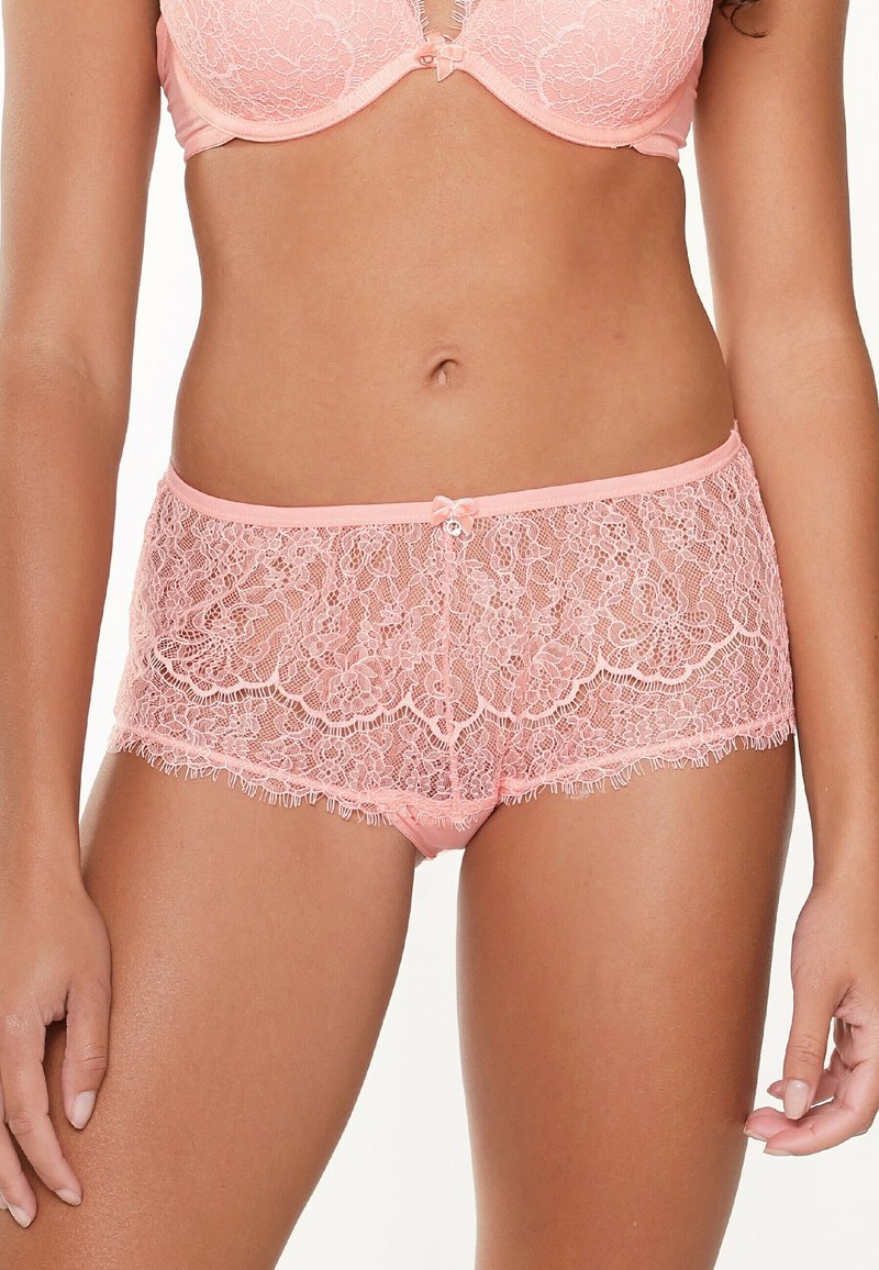 Lace panties in soft pink with floral patterns, featuring a mid-rise cut, scalloped edges, and a small bow accent at the waistband.