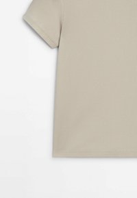 Chemise beige côtelée à manches courtes avec coutures apparentes sur la manche et l'ourlet, présentée sur un fond blanc.