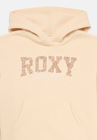 Felpa beige con cappuccio e tasca frontale, con la scritta "ROXY" in lettere a stampa leopardata e "Dal 1990" in corsivo sotto.