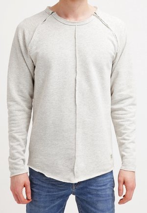 Chemise gris clair à manches longues avec un col rond, des manches raglan et une couture centrale. Fabriquée en tissu doux et texturé ; ourlet arrondi.