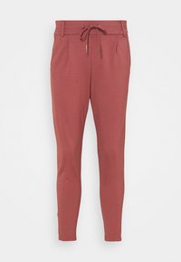 Smal passform i stoft rosa byxor med dragsko i midjan, bälteshällor och sidofickor mot en slät vit bakgrund.