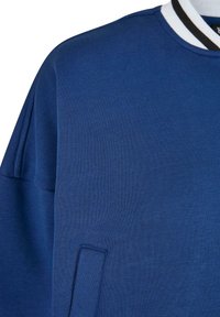 Sudadera azul con cuello redondo, cuello acanalado a rayas blancas y negras, y tela texturizada. Cuenta con un bolsillo en la costura lateral.