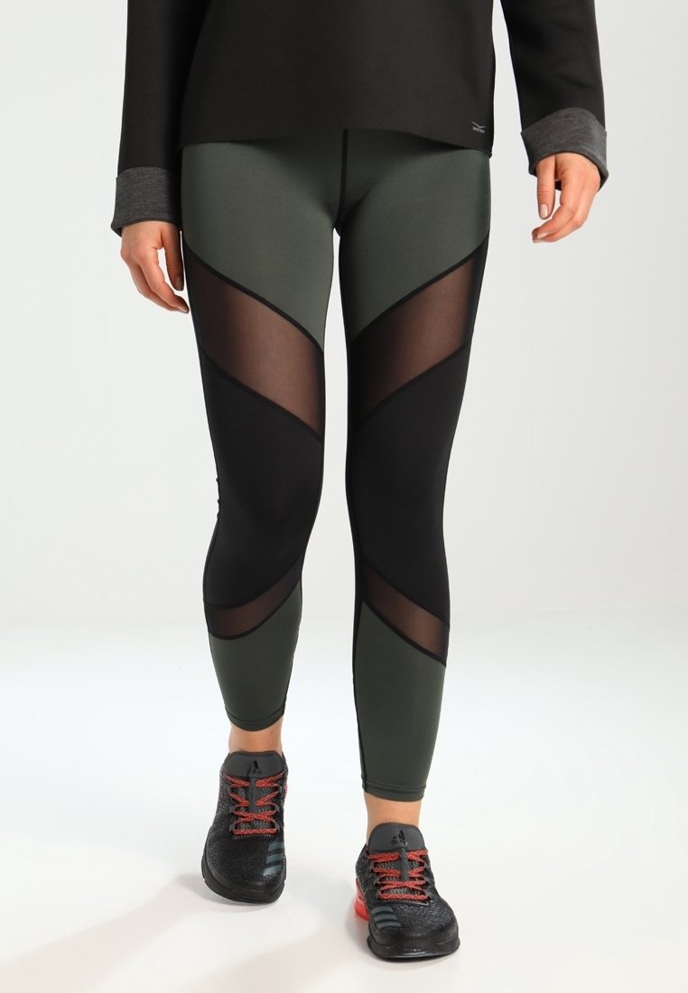 Hoge taille leggings met een olijfgroene en zwarte kleurstelling, voorzien van geometrische doorschijnende panelen en een soepele, rekbare stof.