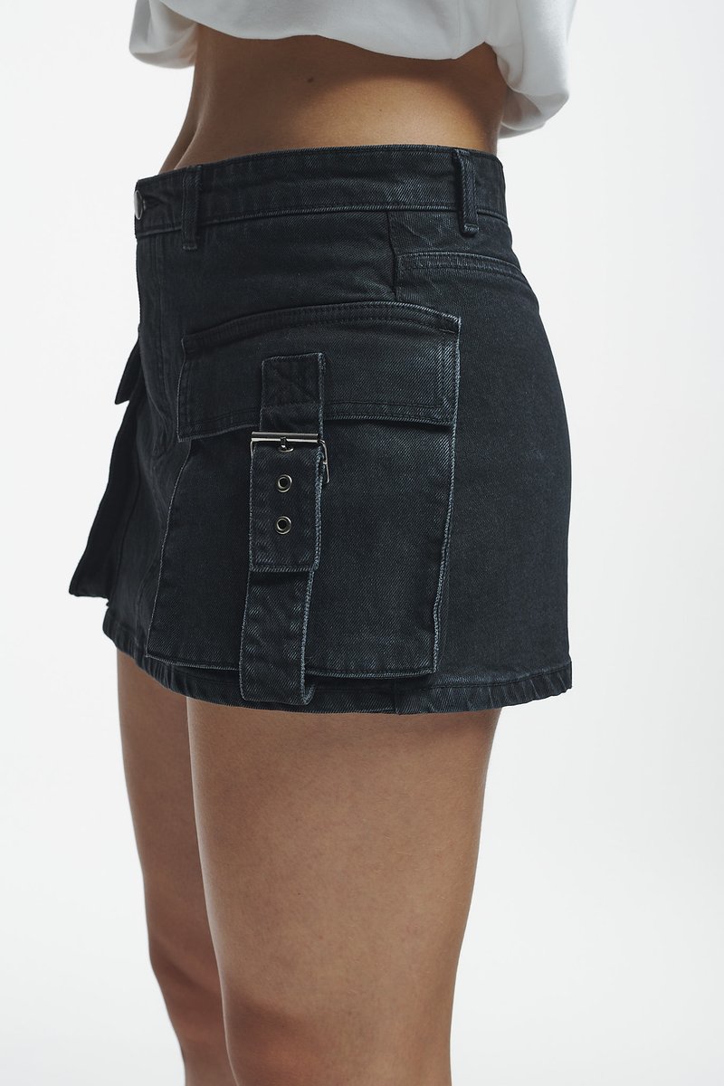 Schwarze Denim-Shorts mit einem taillierten Design, ausgestattet mit einer Seitentasche, Verschlussbeschlägen und einem rohen Saum. Glatte Textur und strukturierte Form.
