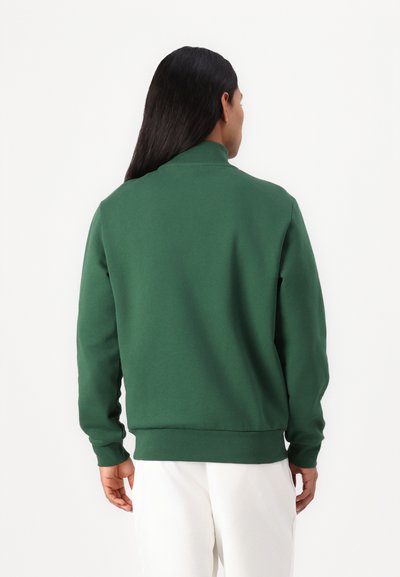 Зелен sweatshirt с висока яка и ръкави с рибена декорация, изработен от меко и гладко платно. Разполага с свободно прилягане и прост дизайн.