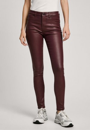 Pantalon en cuir bordeaux slim porté avec des baskets blanches et un top blanc rentré, montré de la taille aux pieds.